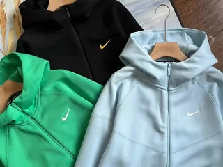 Dark, green and pale blue zip hoodies on hangers